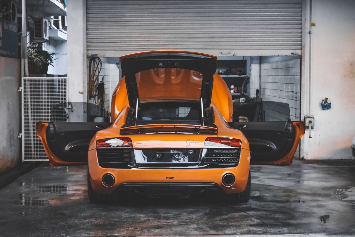Orange sports car with open doors in a garage
